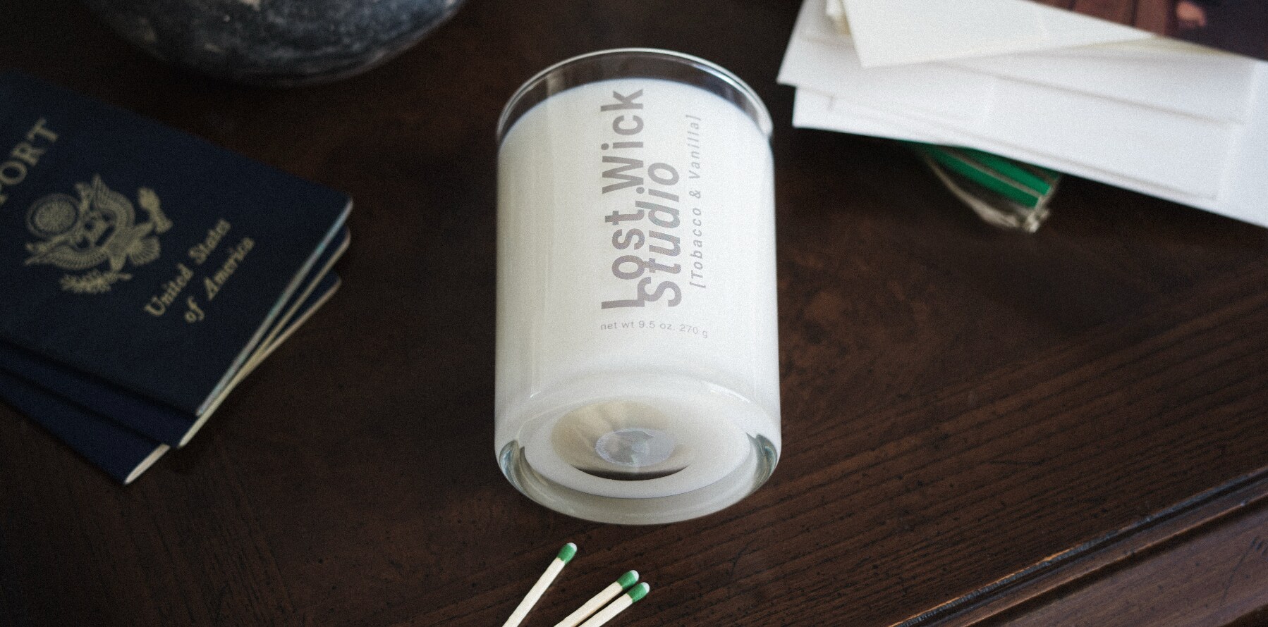 Lost Wick Studio candle photographed on a warm wooden surface with travel details