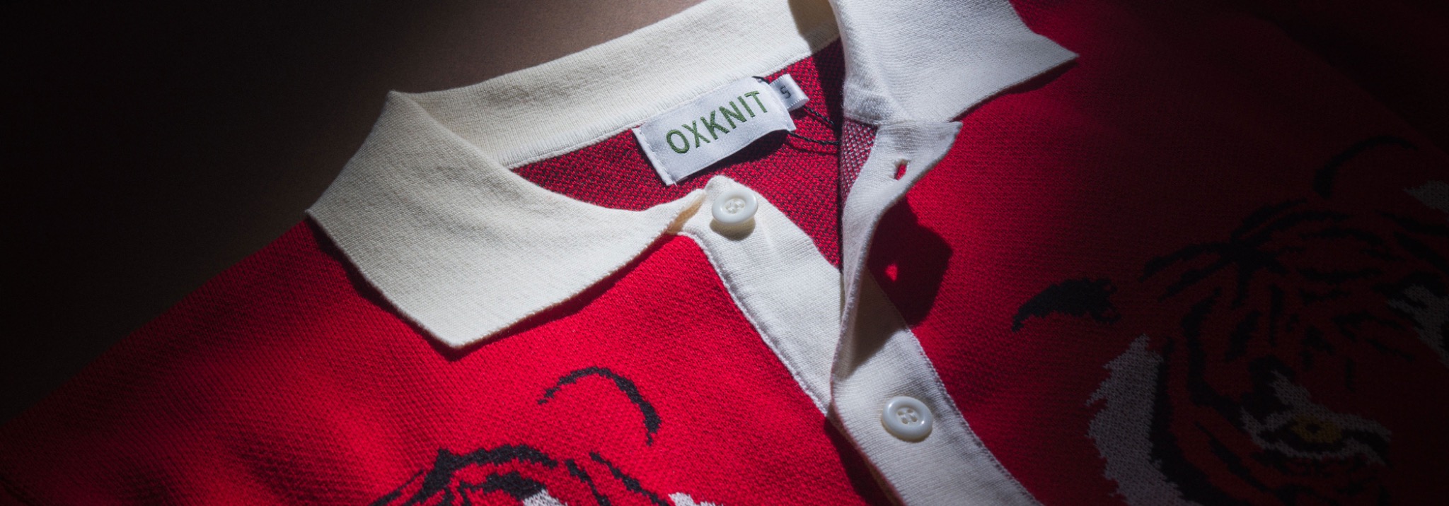Red OXKNIT polo shirt photographed with dramatic directional light