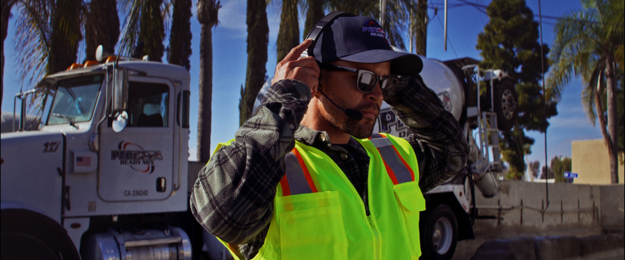 Worker adjusting a Black & Gray headset beside a truck